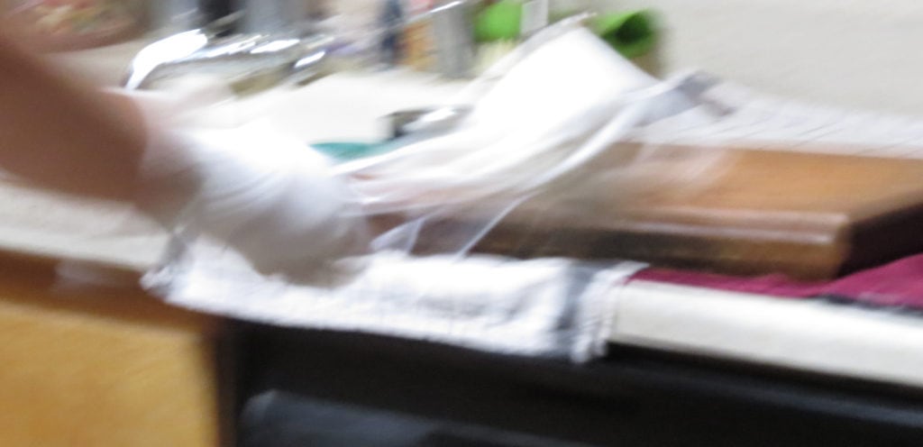 A somewhat blurry image of a white bag being slammed down onto a thick wooden cutting board.
